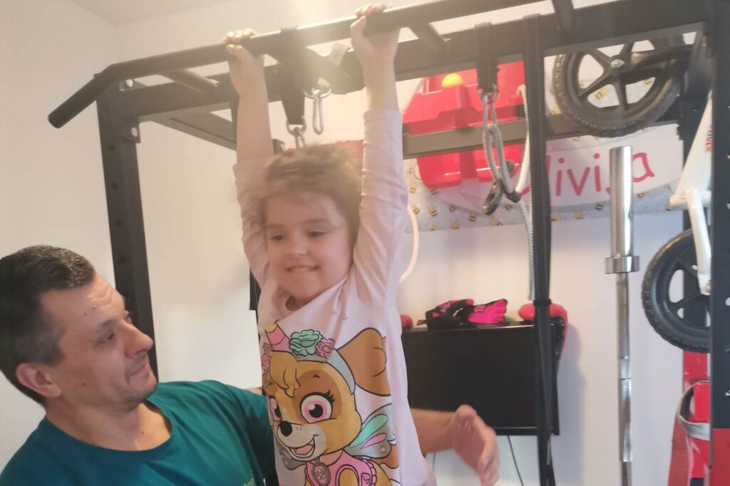 Devojčica radi zgibove, uz tatinu pomoć